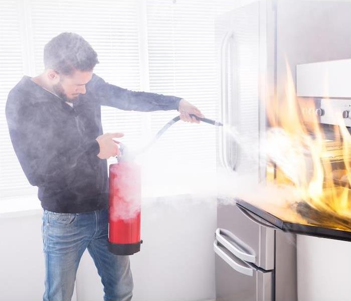 Man using a fire extinguishing a kitchen fire on the counter